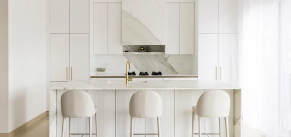 Calacatta marble splashback, range hood and waterfall island in a white kitchen